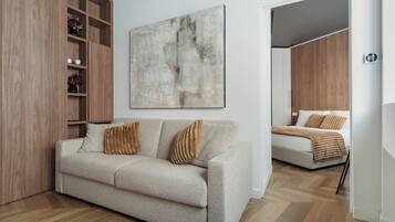 Una habitación moderna con sofá, cama, estanterías de madera y un cuadro abstracto grande.