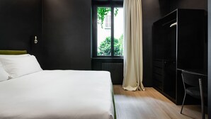 A modern bedroom with a large bed, a window with curtains, a wardrobe, and a chair. - Brera Apartments in City Center (Milan)