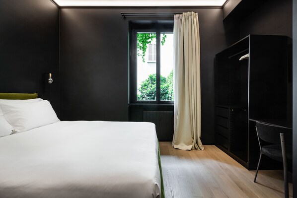 Un dormitorio moderno con una cama grande, una ventana con cortinas, un armario y una silla.