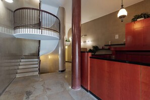 A spiral staircase, a reception desk, and a column in a lobby area. - Brera Apartments in City Center (Milan)