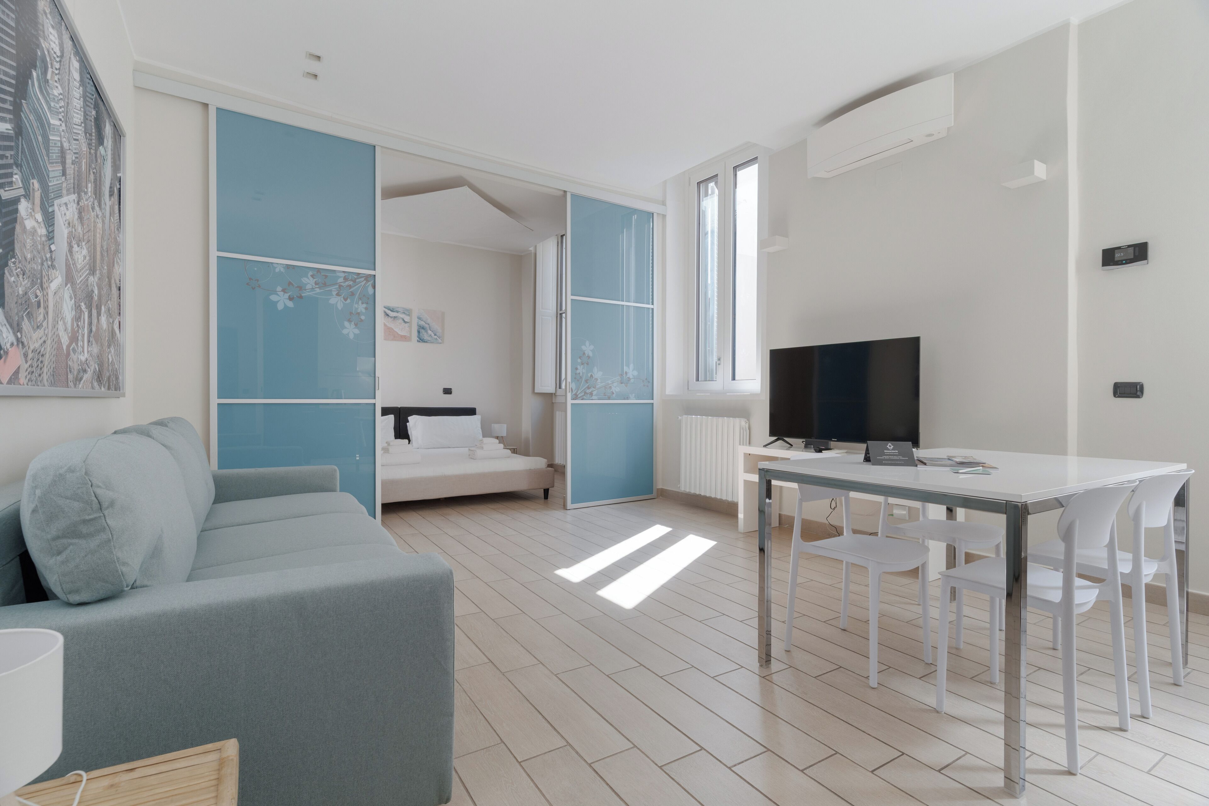 A modern room with a sofa, a TV, a dining table, and a window.