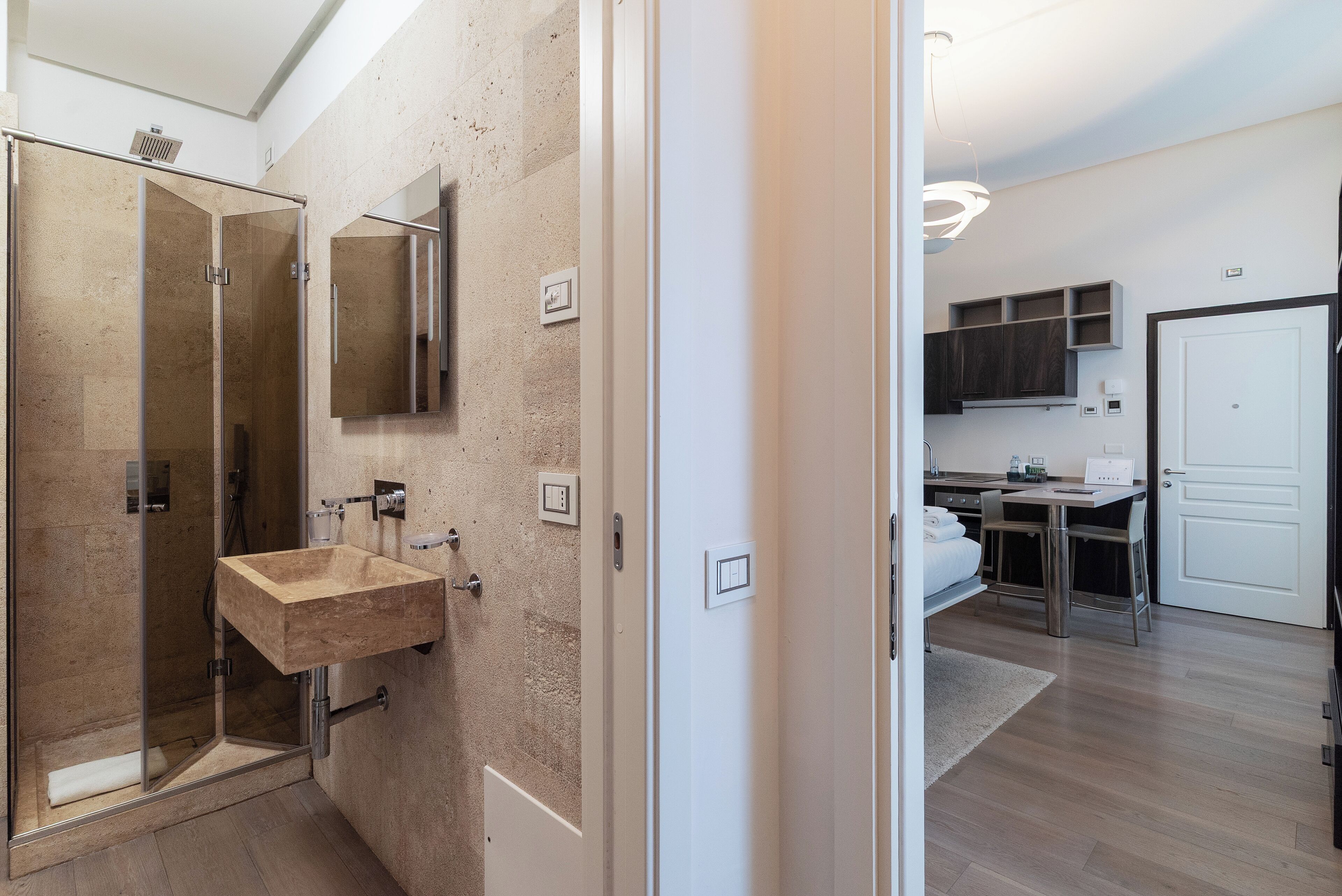 A modern bathroom with a glass shower enclosure, a beige sink, and a mirror.