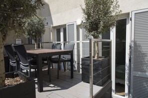 An outdoor patio with a table and chairs, a potted plant, and a sliding glass door leading to a bedroom. - Brera Apartments in City Center (Milan)
