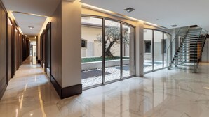 A modern hotel corridor with a glass wall, a staircase, and a marble floor. - Brera Apartments in City Center (Milan)