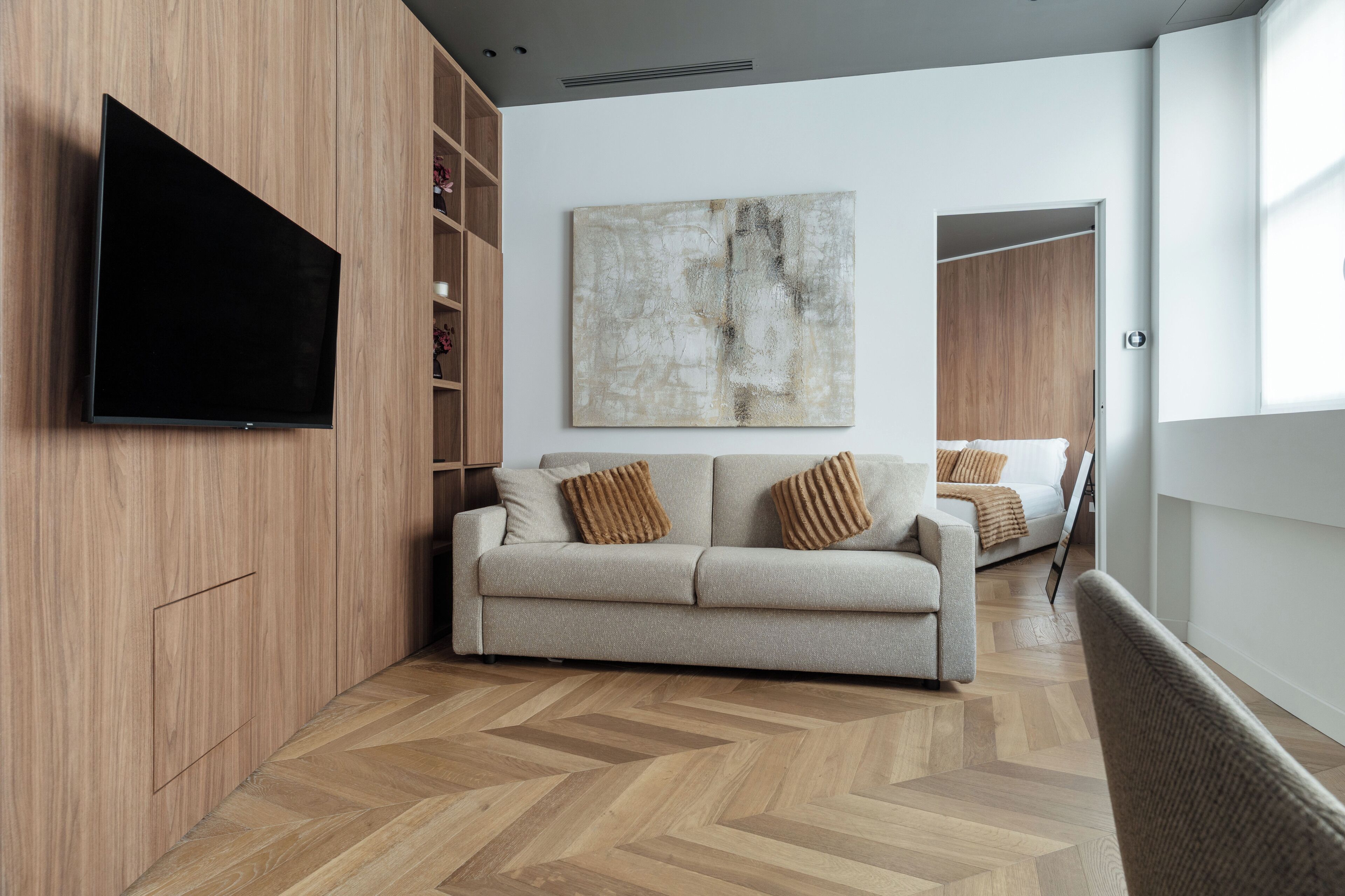 Un salon moderne avec un canapé, un téléviseur à écran plat, un grand tableau abstrait et un plancher en bois.