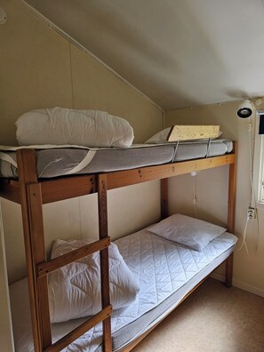 A bunk bed with two levels, each with a mattress and pillows.