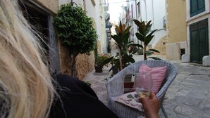 Eine enge Gasse mit einem Korbstuhl und einem Weinglas.