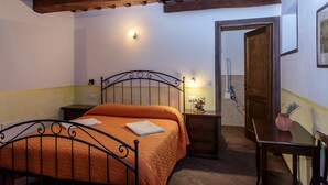 A bedroom with a bed, bedside table, and a wooden door. - Agriturismo Eutopia (San Leo)