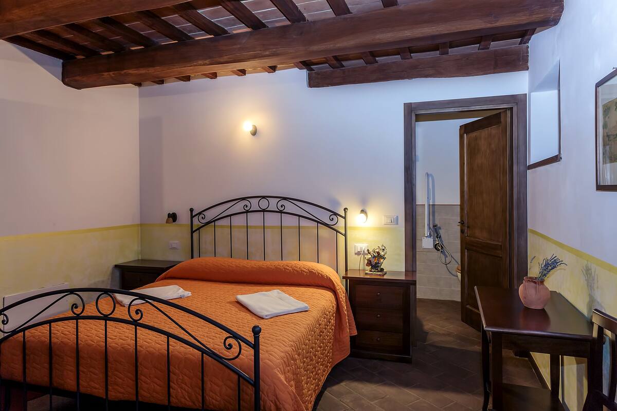 Een slaapkamer met een bed, nachtkastje en een houten deur.