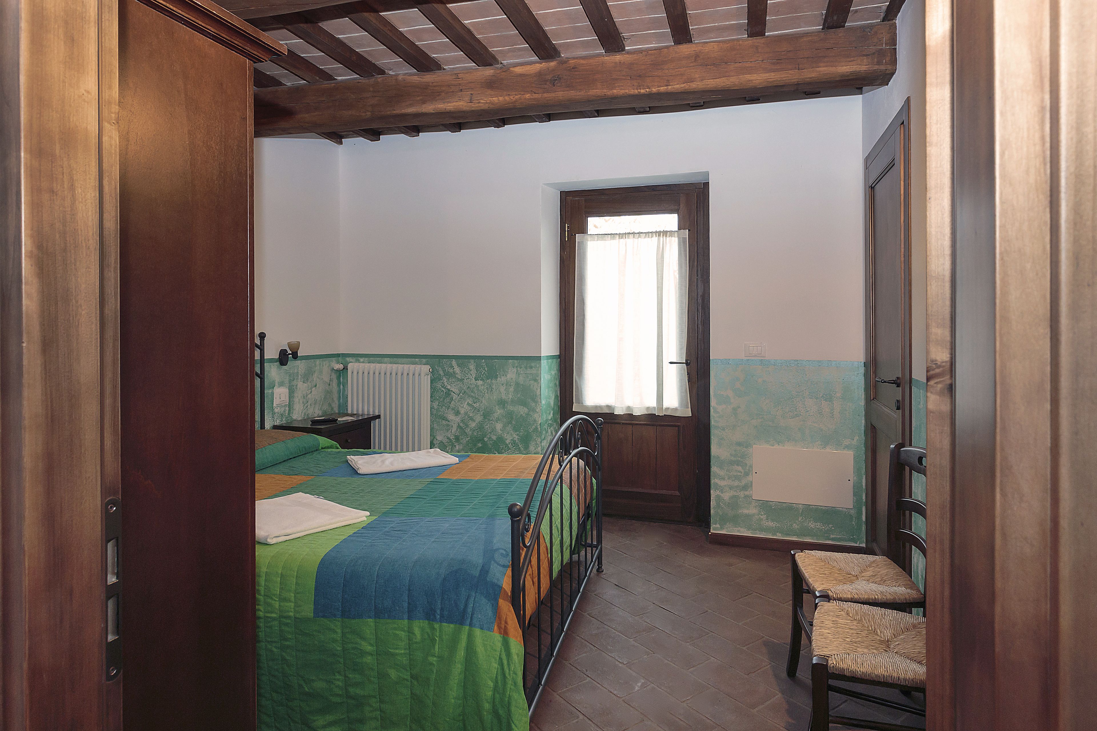 Une chambre à coucher avec un lit, une chaise, une fenêtre et une porte.