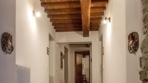 A hallway with wooden flooring, white walls, and a stone accent wall. - Agriturismo Eutopia (San Leo)