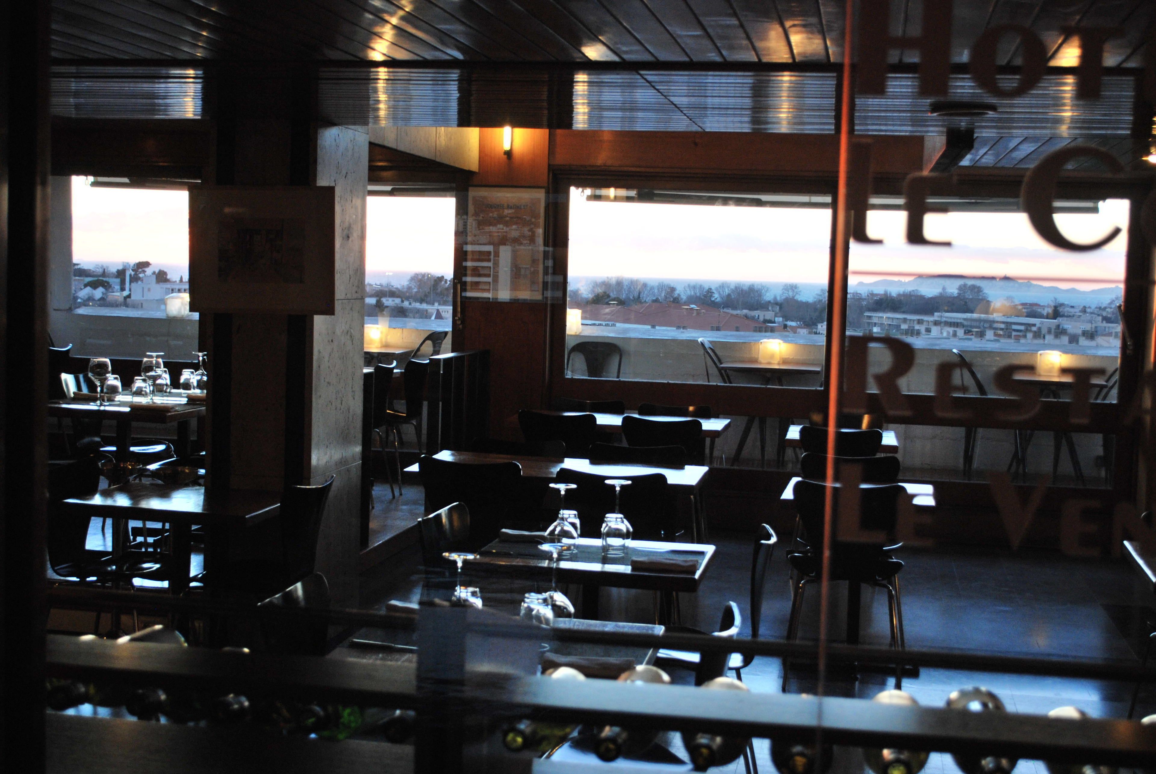 An indoor dining area with tables and chairs, a view of the outside, and a sign that reads "HOTEL".
