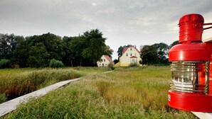 En stig leder fram till en rad hus, och i förgrunden syns ett rött föremål.