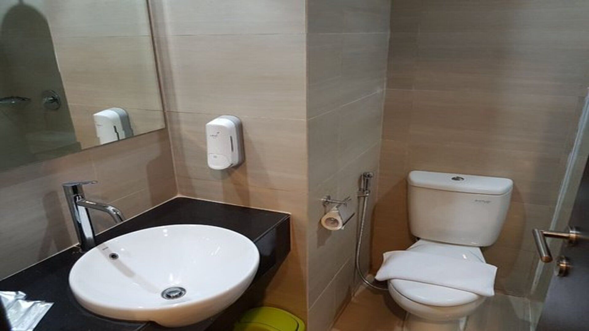 A bathroom with a sink, toilet, and hand dryer.