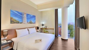 Una habitación de hotel con una cama, un escritorio, una silla, un televisor y un cuadro en la pared.
