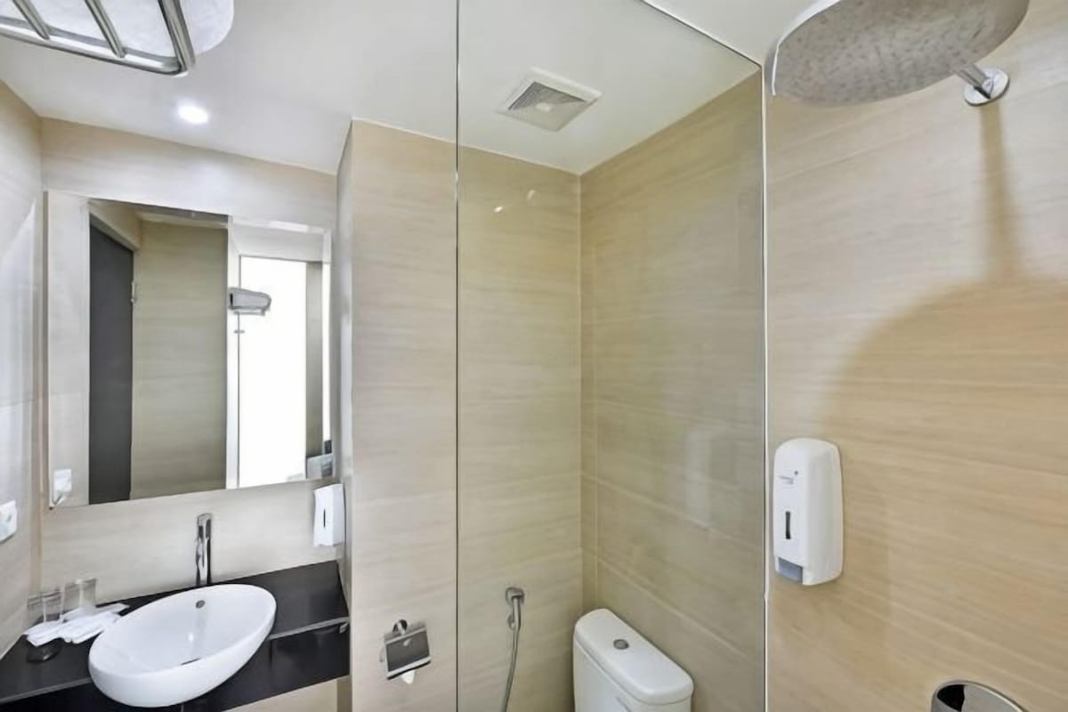 A modern bathroom with a sink, mirror, shower, and toilet.