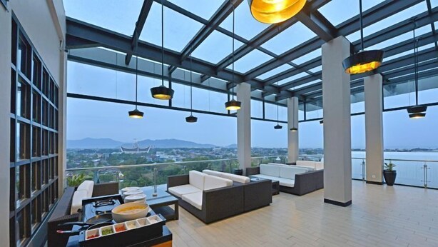 Amplia terraza lounge con mobiliario moderno, comedor y vistas a la ciudad y montañas.