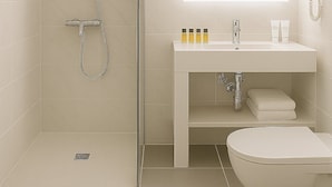 Een moderne badkamer met een douchecabine van glas, een witte wastafel met spiegel en een toilet.