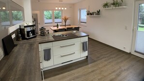 A modern kitchen with a central island, white cabinetry, and a dining area with a table and chairs.