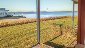 A coastal view from a porch with a grassy lawn, a lamp post, and a distant shoreline. - Amazing apartment in Rechlin with sauna (Rechlin)