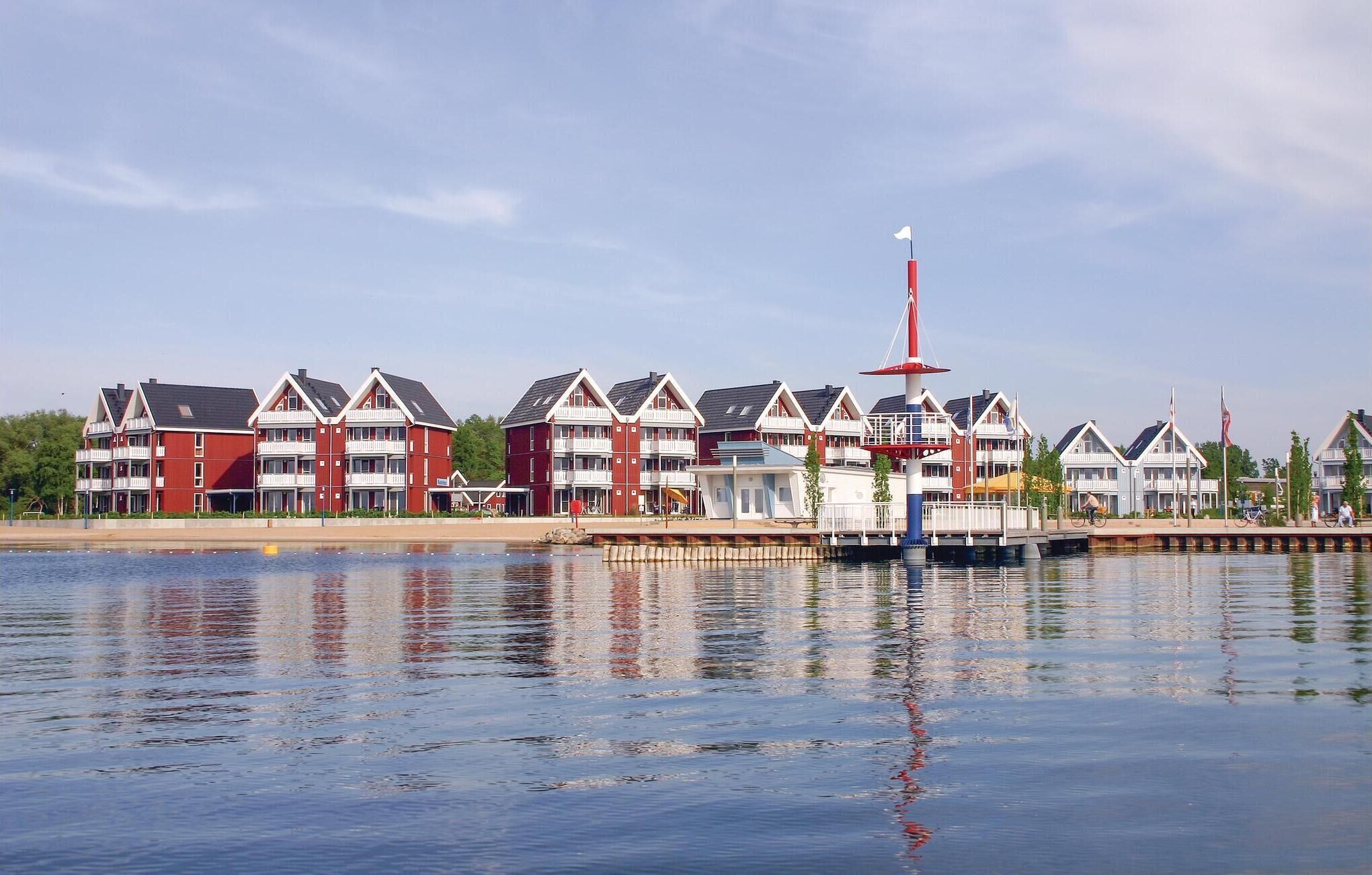 Un hotel frente al agua con varios edificios blancos y rojos, un muelle y un faro.