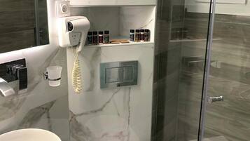 A modern bathroom with a marble vanity, a toilet, and a glass shower enclosure.