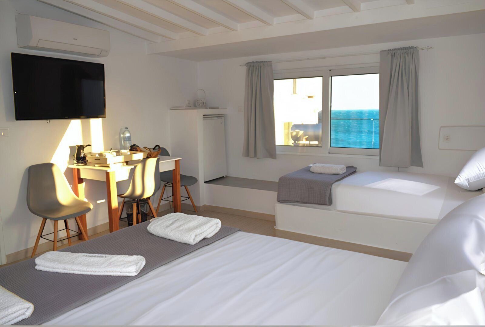 A hotel room with a bed, a desk with a chair, a television, and a window with curtains.