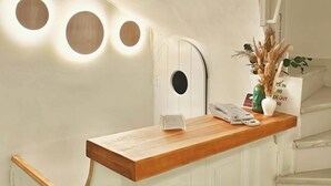 Una recepción con mostrador de madera, un teléfono y un florero con plantas secas.