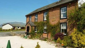 A two-story building with a brick facade, a small porch area, and a visible entrance. - Troutbeck Inn (Penrith)