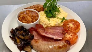 A plate of food including beans, scrambled eggs, bacon, sausage, mushrooms, and tomatoes. - Troutbeck Inn (Penrith)