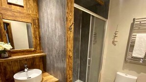 A bathroom with a wooden vanity, a sink, a toilet, and a glass shower enclosure. - Troutbeck Inn (Penrith)