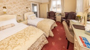 A hotel room with two beds, a desk, a chair, a wardrobe, and a window with curtains. - Haddon House Hotel (Bridport)