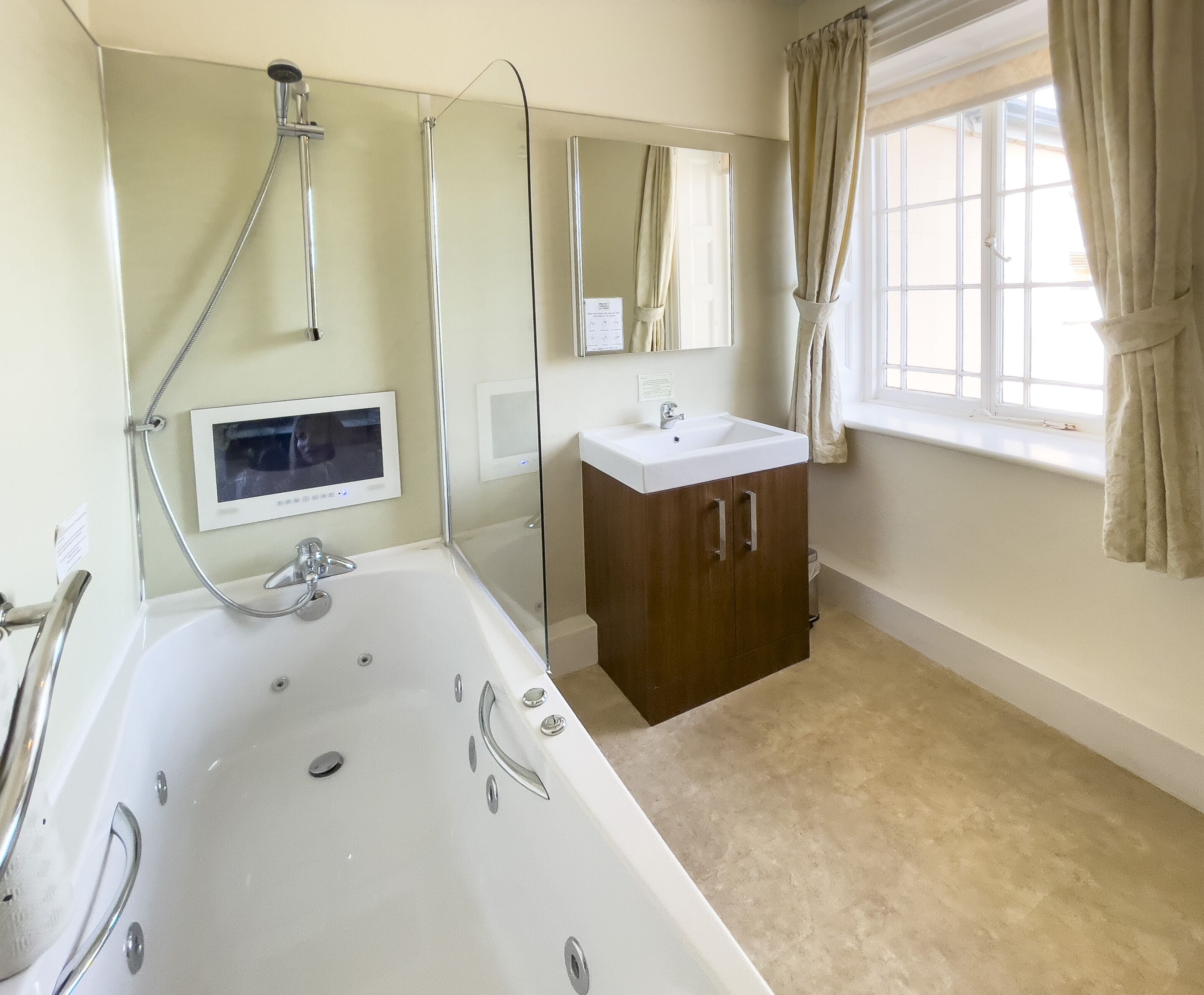 A bathroom with a bathtub, a shower, a sink, and a window with curtains.
