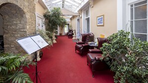 A hotel corridor with a red carpet, stone walls, and leather armchairs. - Haddon House Hotel (Bridport)