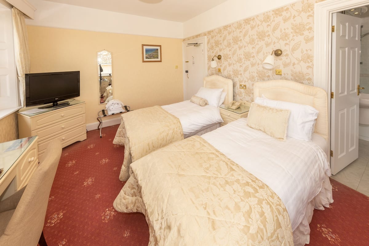 A hotel room with two beds, a television, a desk, and a bathroom door.