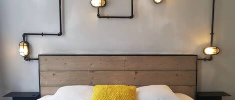 Una cama con cabecera de madera, ropa de cama blanca y una manta amarilla.