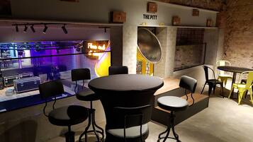 A modern interior with a round table and black chairs, a brick wall, and a neon sign.