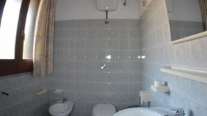 Un baño con techo de madera, un bidé, un inodoro y un lavamanos.