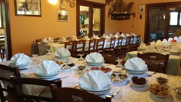 Un comedor con mesas dispuestas para varios invitados, con manteles blancos, platos y copas.