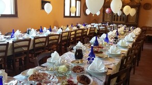 Una larga mesa de comedor dispuesta con varias sillas, manteles blancos y jarrones azules.