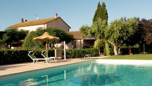 A swimming pool with a clear blue water, surrounded by a deck with lounge chairs and a pergola. - Agriturismo Al Vermigliano (Grosseto)