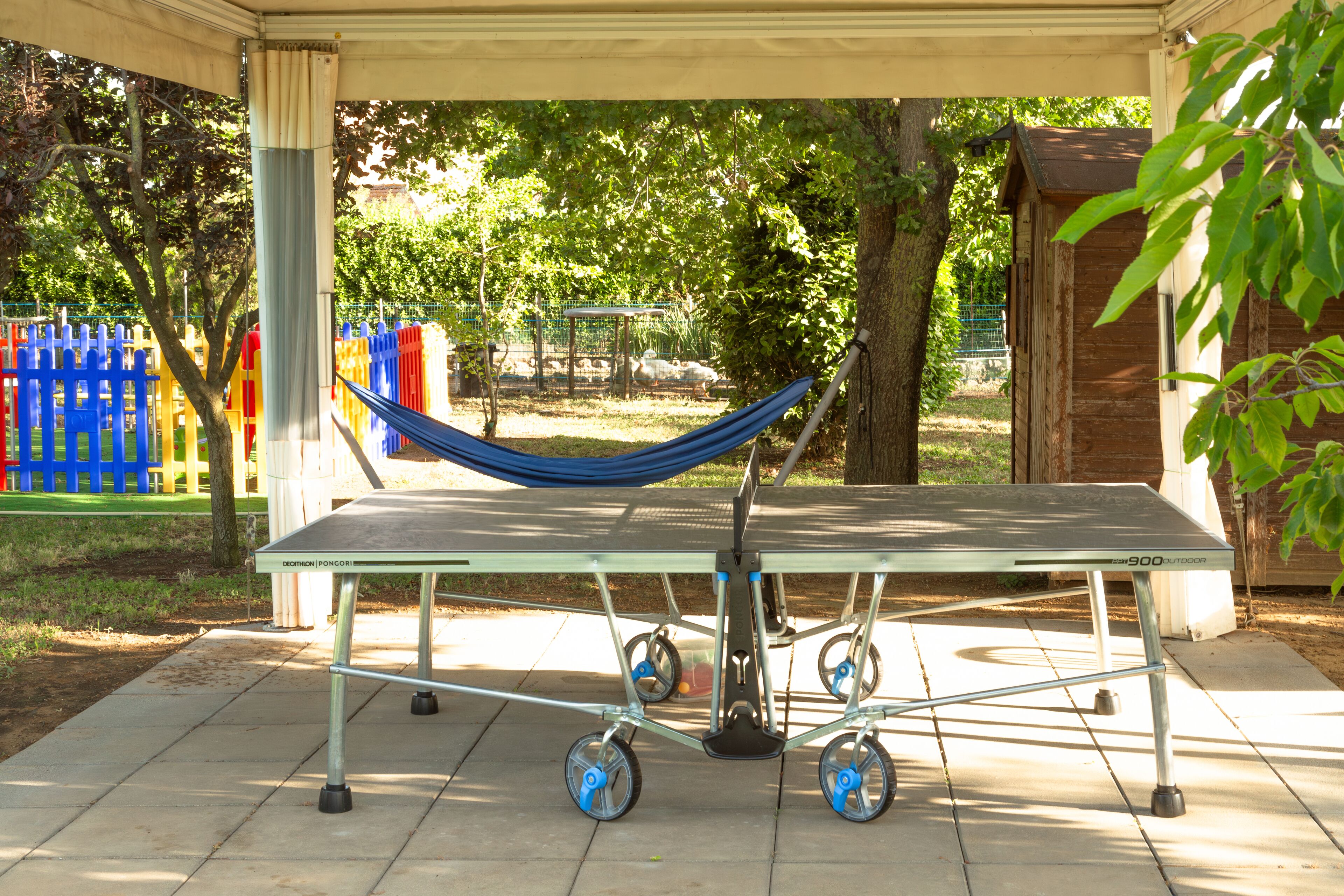 Un espacio al aire libre techado con una mesa y una hamaca.