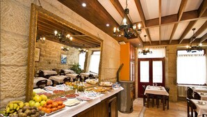 A buffet area with a variety of food items, wooden beams on the ceiling, and a stone wall. - Hotel O Portelo Rural (Allariz)