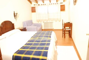 A bedroom with a bed, a chair, a desk, and a radiator.