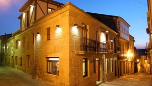 A historic building with a stone facade, multiple windows, and a balcony with a wrought iron railing. - Hotel O Portelo Rural (Allariz)