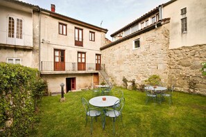 A courtyard with stone buildings, a grassy lawn, and outdoor seating.