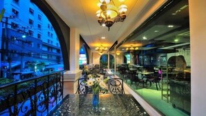 A restaurant with a glass railing, a table with a vase of flowers, and a view of a building outside. - Aspira Skyy Sukhumvit 1 (Bangkok)