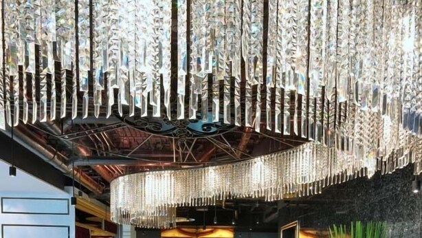 A modern lobby with a black and white patterned floor, a round black leather sofa, and a chandelier with hanging crystals. - Aspira Skyy Sukhumvit 1 (Bangkok)