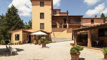 A building with a courtyard, potted plants, outdoor seating, and a stone wall.