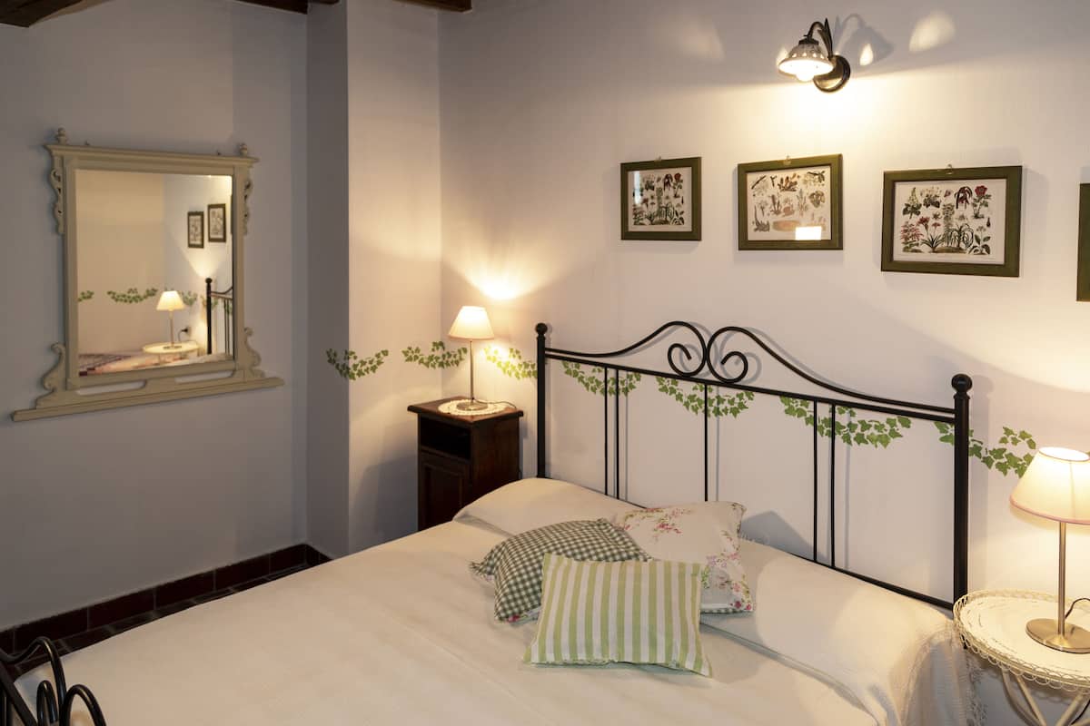 Une chambre à coucher avec un lit, des lampes de chevet, un miroir et des tableaux encadrés accrochés au mur.